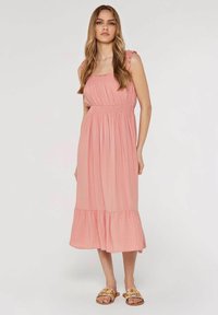 Rosa knälång klänning med en ihopdragen bodice, volangremmar och en utsvängd nederkant. Tillverkad av lätt tyg med rutigt mönster.