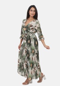 Robe maxi à imprimé floral dans des tons verts et beiges, avec un décolleté en V, des manches longues, une taille à nouer et une jupe fluide plissée.