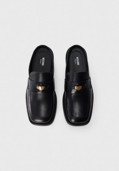 Mustad musta nahast slip-on kingad ruudukujulise nina disainiga, kullatooni aksessuaaride ja tekstureeritud külgede detailidega. Sile pind ja kindel konstruktsioon.