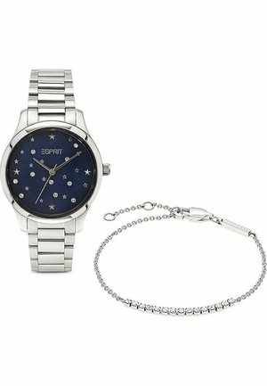 Silberfarbige Armbanduhr mit einem dunkelblauen Zifferblatt, das mit Sternen und Kristallakzenten verziert ist, begleitet von einem zarten silbernen Armband.