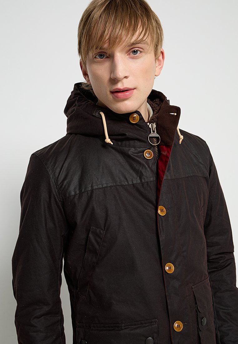 Black jacket with a hood, featuring a mix of materials, wooden buttons, and a textured, contrasting inner lining. Practical design with pockets.