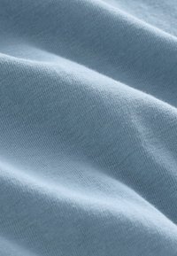 Stof de culoare bleu deschis, cu o textură moale și netedă și un model fin de tricot, evidențiind pliuri și cute delicate.