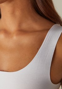 Hvid tanktop med en rundet udskæring, fremstillet af glat bomuldsstof og med en tætsiddende pasform, der fremhæver de naturlige kurver.