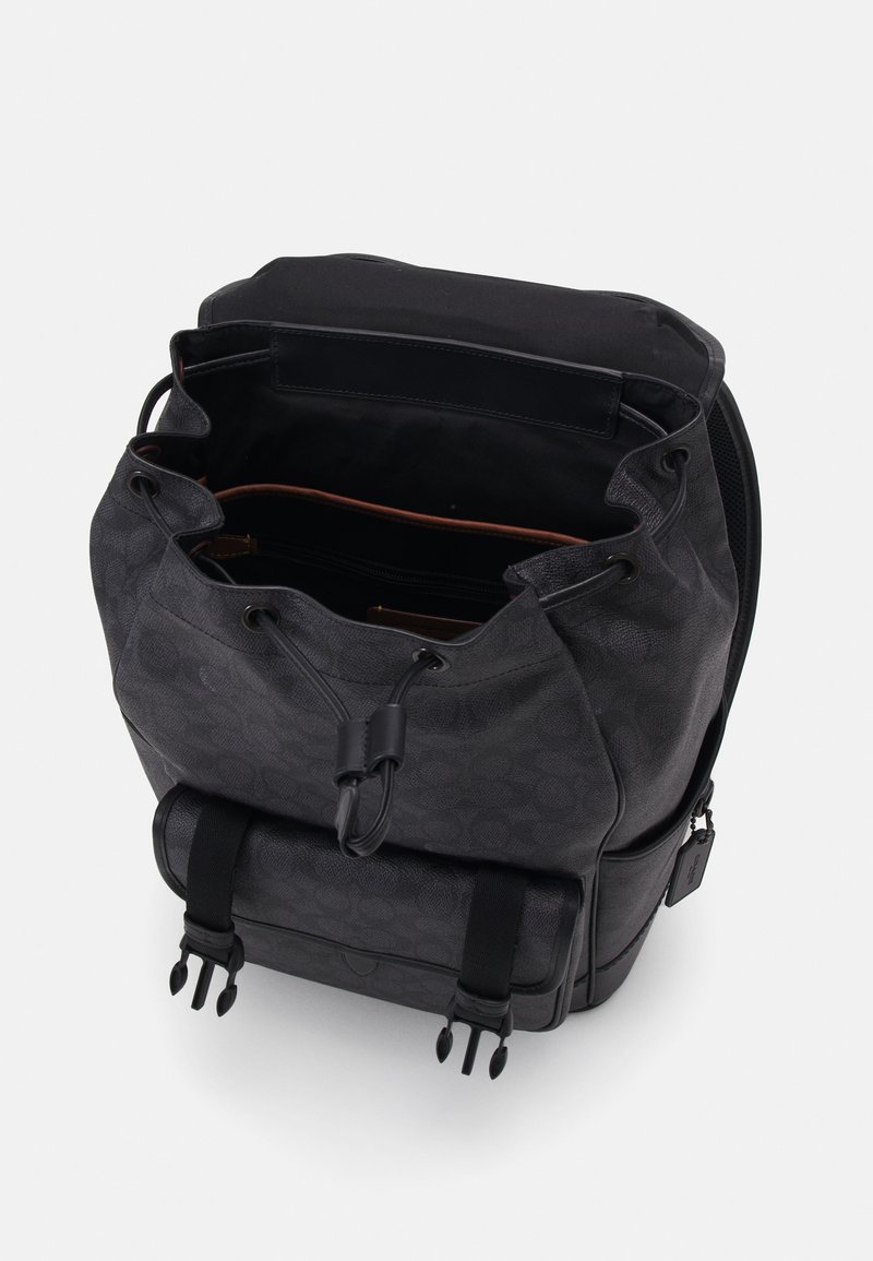 Zaino in tessuto nero con un motivo testurizzato, chiusura a coulisse e scomparti interni. Presenta spallacci regolabili e una tasca inferiore.