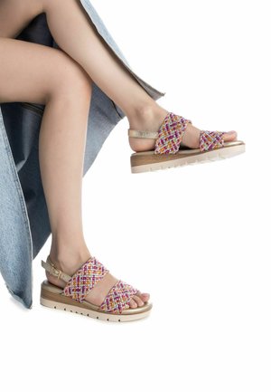 Las sandalias trenzadas presentan un empeine texturizado de múltiples colores con acentos en rosa, amarillo y crema, una cómoda suela de corcho y una correa ajustable en el tobillo.