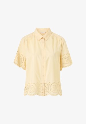 Light yellow short-sleeve button-up blouse with collar and eyelet cutout floral patterns on sleeves and hem.