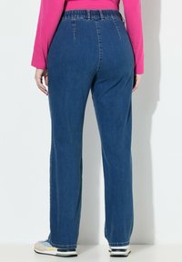 Spodnie jeansowe o niebieskim odcieniu, z wysokim stanem i elastycznym paskiem w pasie. Prosty krój nogawek z widocznym przeszyciem i schludnym wykończeniem.