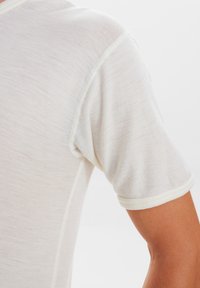 Letvægts, kremfarvet t-shirt med korte ærmer, der har en blød tekstur og kontrastdetaljer omkring halsudskæringen og ærmerne.