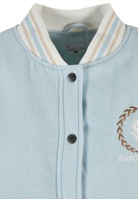 Svetlo modrá fleece bunda s rebrovaným bielym golierom, ktorý obsahuje béžové a svetlomodré pruhy, cvočkové gombíky a vyšívanú logovú ozdobu.