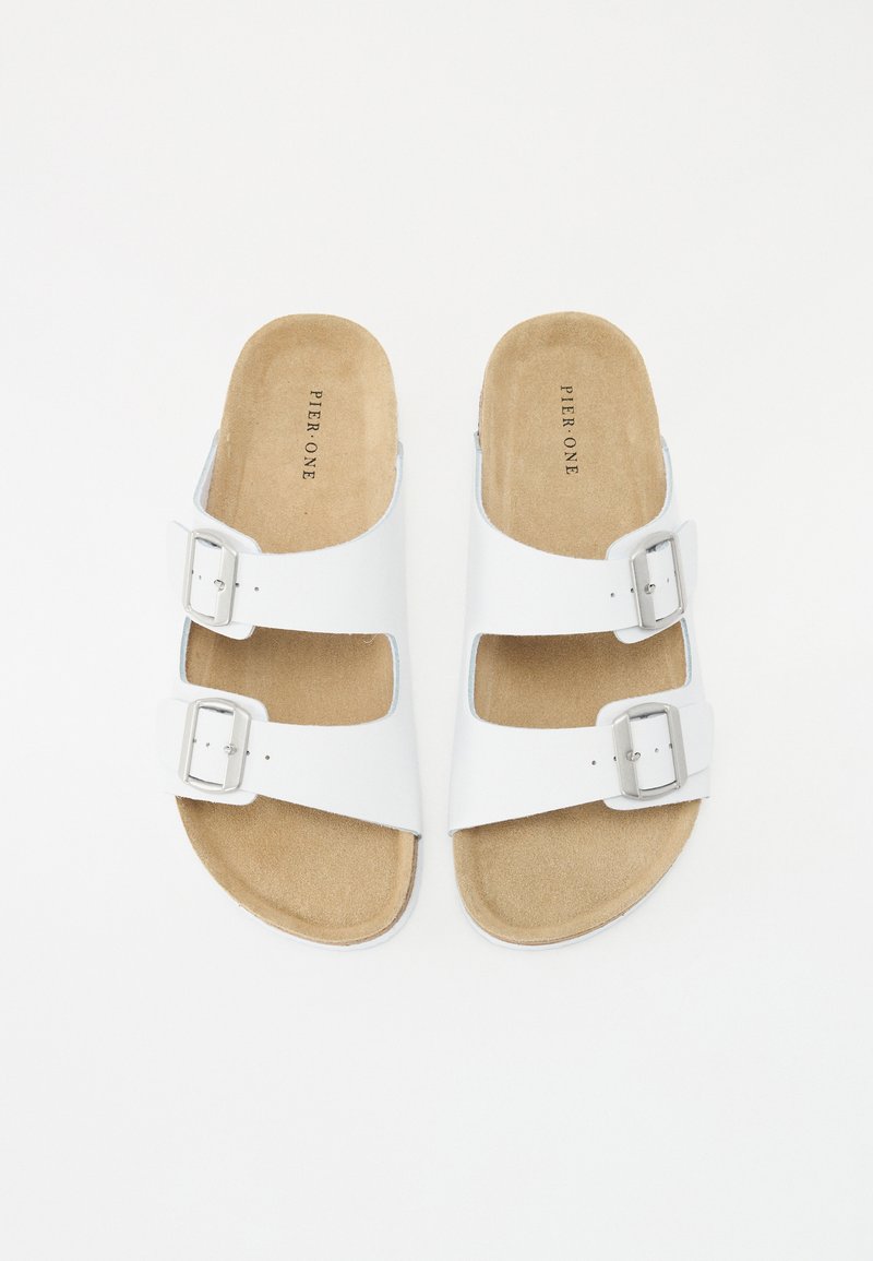 Sandales à glissière blanches avec deux boucles en argent réglables. Semelle intérieure douce couleur tan avec une texture en daim, semelle plate et design à bout ouvert.