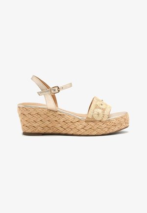 Sandalias de cuña con base trenzada similar a paja, tira beige y parte superior texturizada tejida con bordado floral y pequeños adornos.