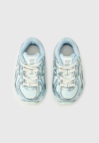Lyseblå sportssko med mesh og glinsende detaljer, med hvite lisser og polstret tunge for komfort. Rundet tådesign.