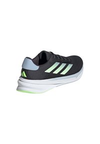 Black athletic shoe with green accents, mesh upper, three white stripes, padded collar, and a lightweight sole with a textured finish.