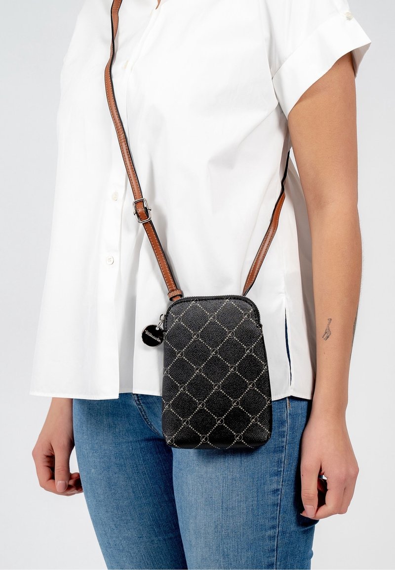 Czarna pikowana torba na ramię z regulowanym brązowym paskiem, ozdobiona wzorem splecionych kółek oraz małym dekoracyjnym zawieszką.