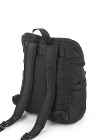 Mochila negra acolchada con correas ajustables y asa superior. Presenta una tela suave y costuras angulares distintivas a lo largo de los lados.