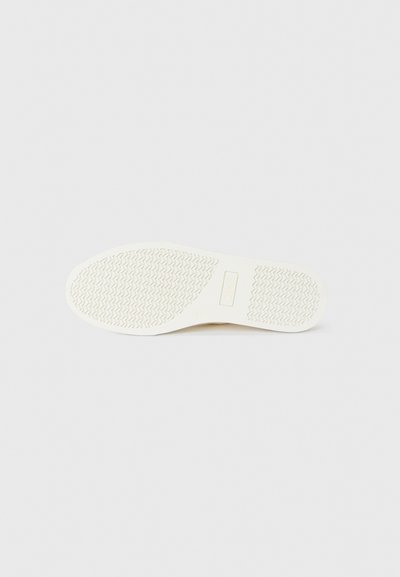 White rubber shoe sole featuring a textured design with a zigzag pattern, including a logo imprint in the center and smooth edges.