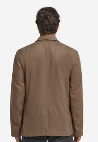Braune maßgeschneiderte Jacke aus glattem Stoff mit einem Reverskragen, langen Ärmeln und einem einzelnen Schlitz auf der Rückseite.