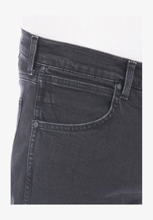 Jeans de mezclilla negra con un diseño clásico de 5 bolsillos, con una cintura de altura media y costuras visibles a lo largo de las costuras.