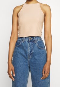 Crop top rosa chiaro con un design aderente e una texture a coste. Abbinato a pantaloni corta in denim blu a vita alta con tasche standard.