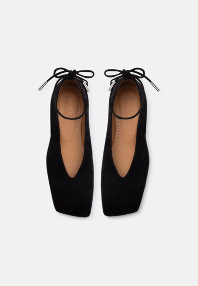 Μαύρες μπαλαρίνες από σουέτ με τετράγωνα μύτη, δεσίματα στον αστράγαλο και ταμπά εσωτερικές σόλες με ανάγλυφο όνομα επωνυμίας σε λευκό φόντο.