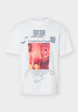 Άσπρο μπλουζάκι Nike με κόκκινο γραφικό ενός ατόμου που φοράει γυαλιά και δείχνει προς τα πάνω, κείμενο "Be Unique" από πάνω και κυματιστό λογότυπο Nike από κάτω.