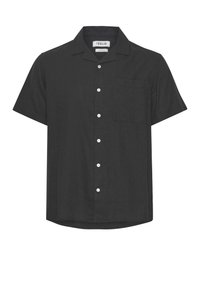 Chemise noire à manches courtes en tissu texturé avec un col, une poche avant et des boutons blancs centrés. L'ourlet présente une légère courbe.