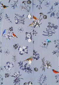 Jasnoniebieska koszula na guziki z pionowym wzorem w paski, ozdobiona różnorodnymi kwiatowymi i ptasimi ilustracjami w różnych kolorach i teksturach.