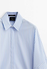 Chemise boutonnée à rayures verticales bleu et blanc avec un col classique, des manches courtes et une patte de boutonnage lisse à l'avant.
