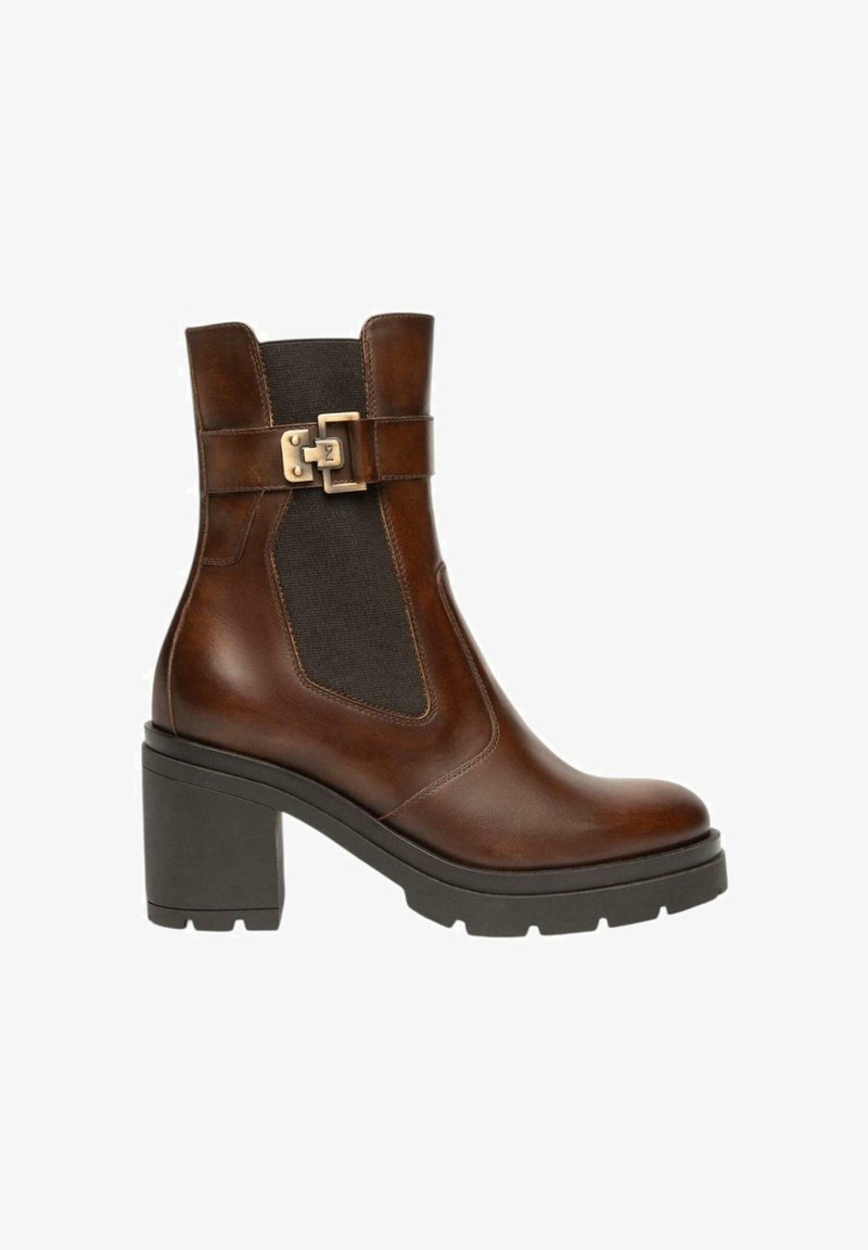 Stivale alla caviglia in pelle marrone con tacco a blocco, pannello laterale elastico nero e cinturino decorativo con fibbia dorata su sfondo bianco.