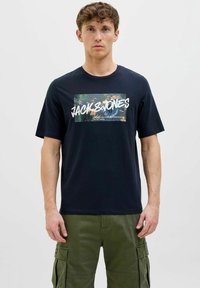 Tumesinine puuvillane t-särk, millel on troopilised elemendid kujutav graafiline trükk, "JACK & JONES" julgete valgete tähtedega, lühikesed varrukad ja ümar kaelus.