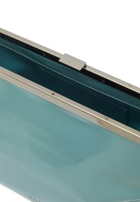 Tyrkysová kožená kabelka na ruku s lesklým povrchem, stříbrným kovovým rámem a uzávěrem na klips. Interiér má hladký, kontrastní podšívku.