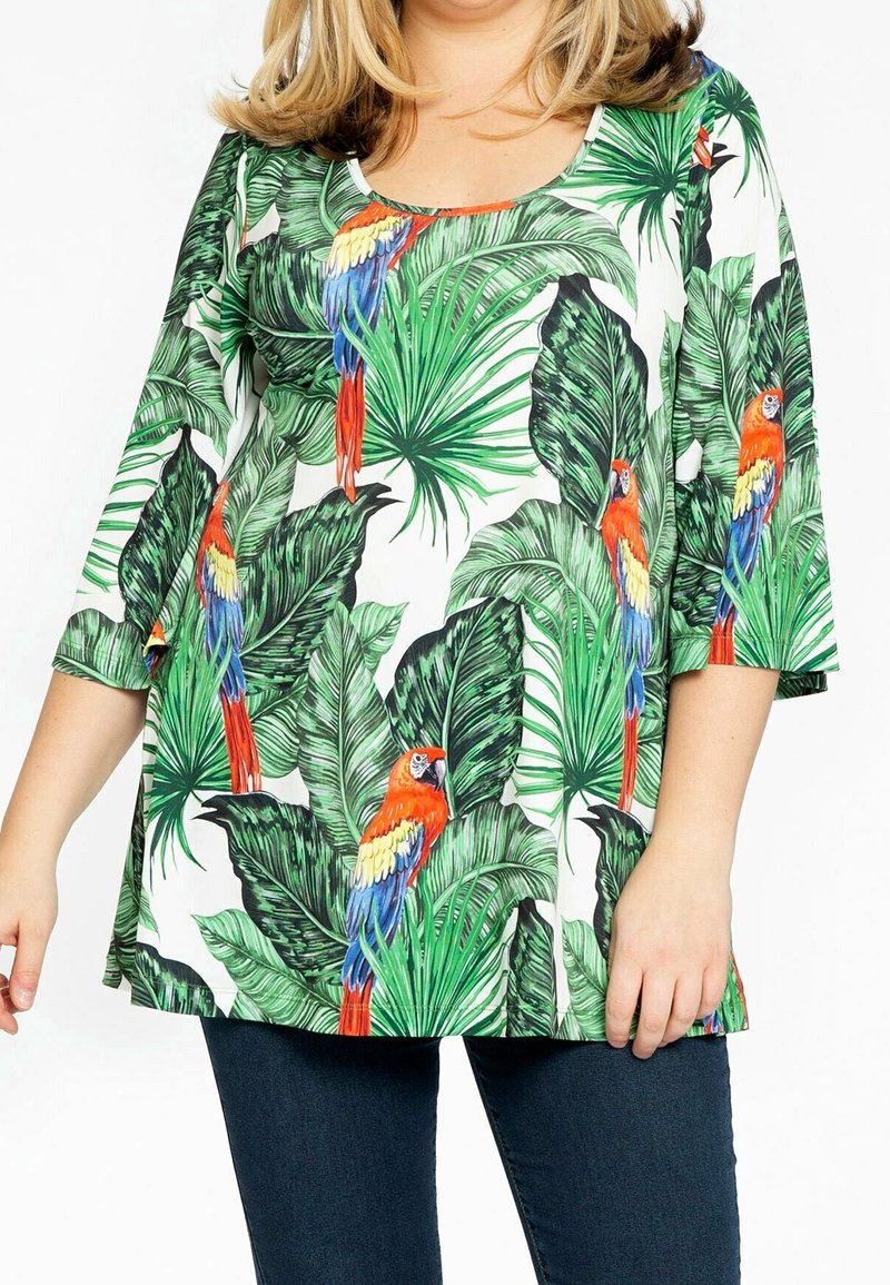 Haut à imprimé floral avec des feuilles vertes et des perroquets rouges, bleus et jaunes vifs. Il dispose d'un décolleté arrondi et de manches trois-quarts.