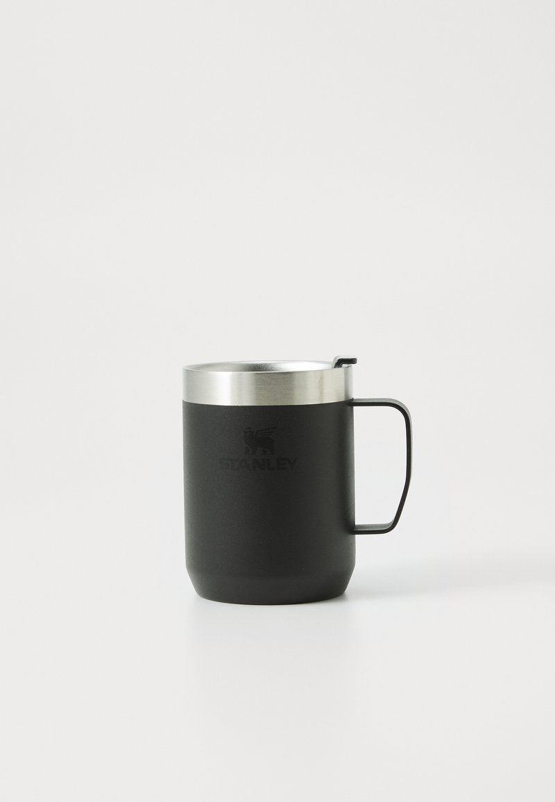 Tasse en acier inoxydable noir avec un couvercle métallique argenté, dotée d'une poignée robuste et du logo "STANLEY" en relief sur le côté.