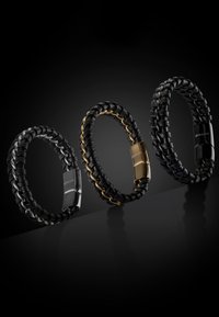 Three braided leather bracelets in black, featuring metallic accents in silver, gold, and black. Each has a distinctive clasp design.