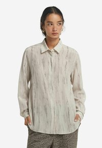 Långärmad skjorta i ljus krämfärgad tyg med ett vertikalt randigt mönster i nyanser av brunt, med klassisk krage och avslappnad passform.