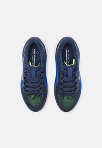 Baskets de course navy avec des accents bleus, tige en mesh, détails verts à motifs, fermeture à lacets et semelle intermédiaire blanche.