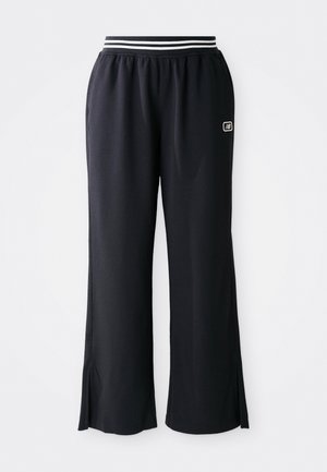Pantalons de sport noirs avec une coupe évasée, ceinture élastique avec des rayures noires et blanches, et fentes sur le bas.