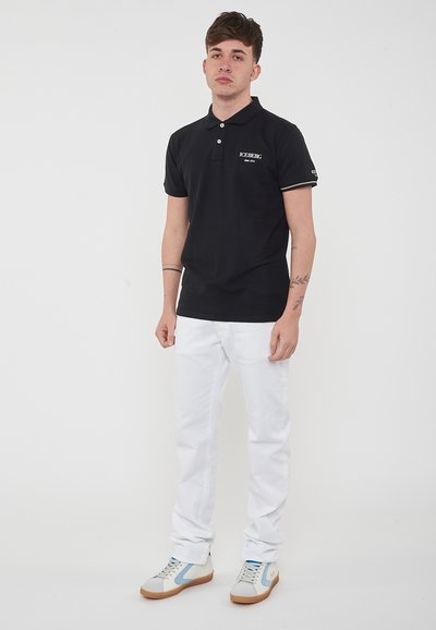 Polo nero a maniche corte, con cuciture bianche e logo "ICEBERG". Abbinato a pantaloni bianchi e sneakers casual.