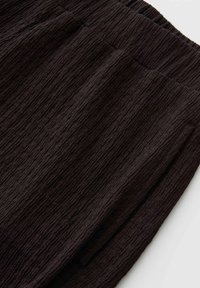 Schwarze, strukturierte Stoffhose mit elastischem Bund und seitlichen Schlitztaschen, gezeigt auf hellem Hintergrund.