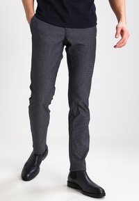 Grå mönstrade byxor med smal passform, tillverkade av textil med struktur. Matchas med svarta läderankelstövlar. Framtida fickor med skräddarsytt utseende.