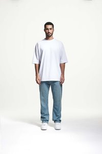 Witte oversized T-shirt met korte mouwen, gecombineerd met lichtblauwe denim jeans en witte sneakers. Eenvoudig ontwerp, casual uitstraling, minimale details.