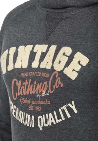 Gray sweatshirt featuring cream and brown printed text. Design includes “VINTAGE” and “CLOTHING CO” with a distressed texture.