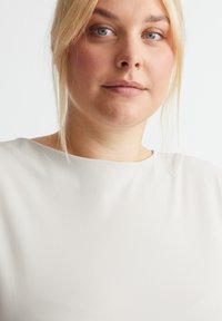 Hellbeige Oberteil mit glatter Textur und rundem Kragen, zeichnet sich durch eine entspannte Passform und minimalistisches Design aus. Geeignet für Freizeitkleidung.