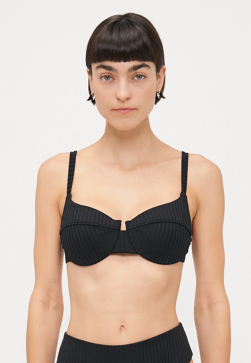 Čierny bikiny top s vypchávkami, širokými ramienkami a detailom stredového švu. Hladká textúrovaná tkanina, minimalistický dizajn.