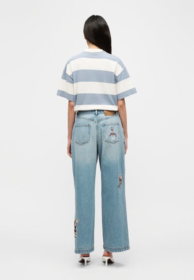 Ριγέ μπλε και λευκό κοντομάνικο μπλουζάκι σε συνδυασμό με ανοιχτόχρωμο μπλε τζιν με χαλαρή εφαρμογή, διακοσμημένο με κεντήματα και φθαρμένες λεπτομέρειες.