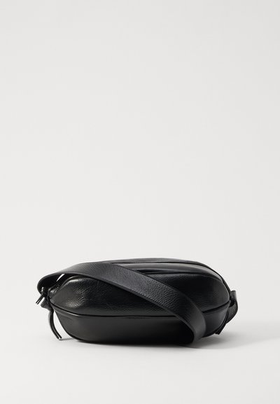 Schwarze Leder-Crossbody-Tasche mit runder Form, strukturiertem Oberflächenfinish, verstellbarem Träger und Reißverschluss, ausgestattet mit dezenten Nahtdetails.