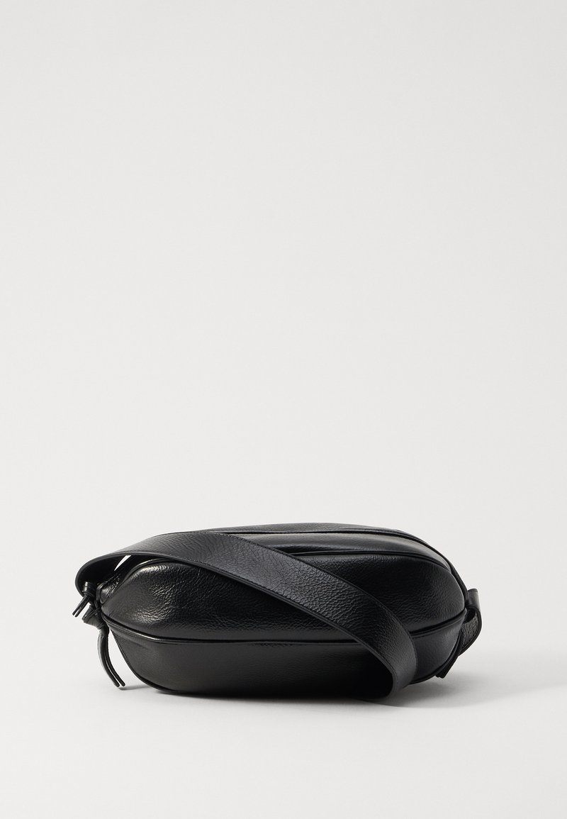 Borsa a tracolla nera in pelle con forma arrotondata, superficie texturizzata, tracolla regolabile e chiusura con zip, caratterizzata da dettagli di cucitura discreti.