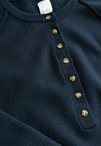 Dark navy knit sweater featuring a rounded collar, seven gold-tone buttons down the front, and subtle texture. Label visible at the collar.