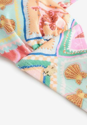 Värvikas kangas, millel on muster merekarpide ja keeristega pastelltoonides, peal kuldne dekoratiivne detail. Tekstuuriga pind, pehme viimistlusega.