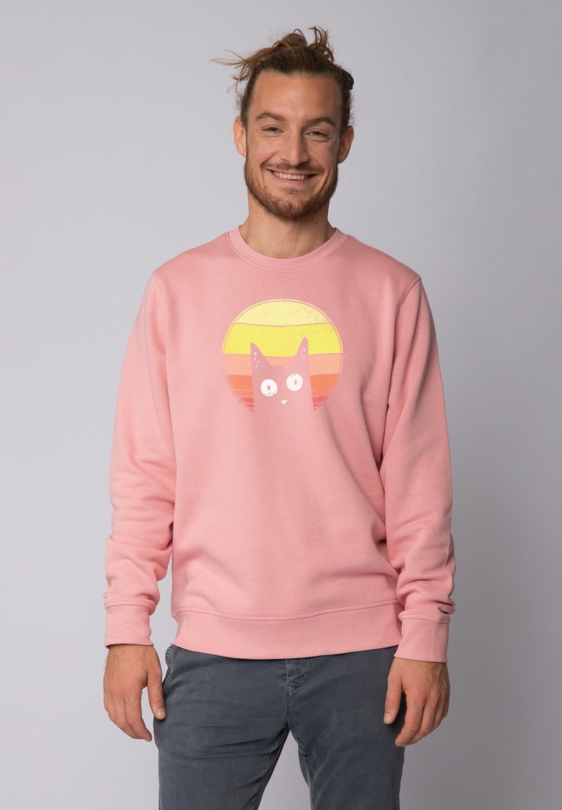 Rosa Sweatshirt mit einem grafischen Druck einer Katze vor einem Sonnenuntergangshintergrund mit horizontalen Streifen in Gelb, Orange und Pink. Weicher Stoff.